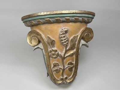 un vase doré et vert posé sur une surface blanche
