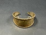 a close up of a gold cuff bracelet on a table