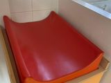 a red seat that is on top of a wooden table