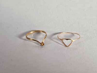 une paire de bagues en or posées sur une surface blanche