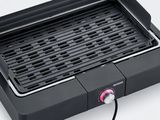 un gros plan d'un gril posé sur une surface blanche, avec un bouton rose