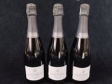 trois bouteilles de champagne posées côte à côte sur une table
