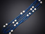 a blue and white beaded necklace with pearls on a black background