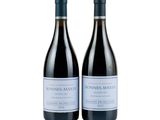 two bottles of wine sitting next to each other on a white surface