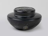 un vase noir muni d'un couvercle noir, posé sur une surface blanche