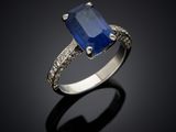 a blue sapphire and diamond ring on a black surface