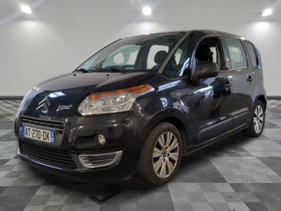 La petite camionnette noire est garée sur un sol en carrelage à damier.