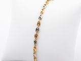 un bracelet en or orné de diamants noirs et blancs, présenté sur un coussin blanc
