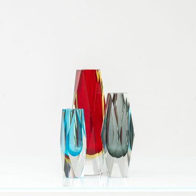 trois vases en verre posés sur une étagère, sur une surface blanche