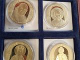 six gold coins in a blue case with a picture of a woman and a man