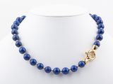 a blue beaded necklace on a mannequin with a gold clasp