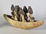 plusieurs figurines représentant des personnes dans un bateau en bois, posées sur une surface blanche