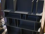 a black book shelf with four bins on top of it