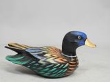 a small wooden duck that is sitting on the ground