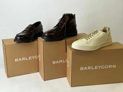 three pairs of shoes sitting on top of boxes on a white surface