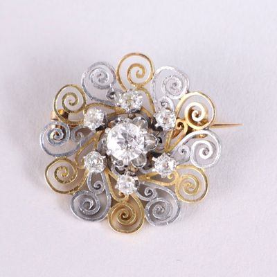 une image représentant une broche en diamant et en or posée sur une surface blanche
