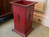 a red planter sitting on the floor in front of a cabinet