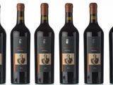 six bottles of wine are lined up on a white surface