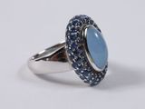 a close up of a ring with a blue stone surrounded by blue sapphires