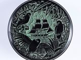 une assiette noire et verte sur laquelle est représenté un bateau