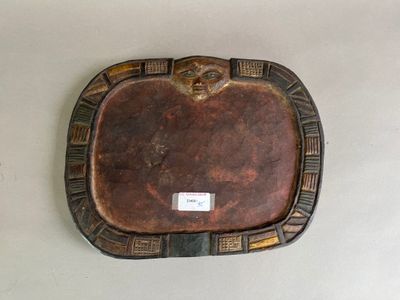 une assiette marron sur laquelle est représenté un visage, posée sur une table