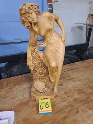 une statue représentant une femme tenant un poisson sur une table en bois