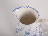 a small blue and white pitcher on a white table