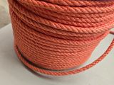 une corde orange surmontée d'une bobine violette, posée sur une table
