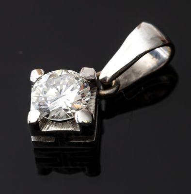 une photo d'un pendentif en diamant posé sur une surface noire