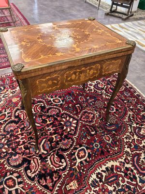 une table ancienne avec un plateau en bois posée sur un tapis dans une pièce