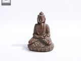 un gros plan sur la statue d'une personne assise sur une surface blanche