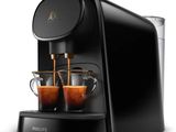 une machine à café noire avec deux tasses de café devant elle