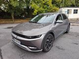 La voiture grise est garée sur le parking à côté de la maison.
