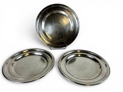 deux assiettes en argent avec leurs couvercles sont posées sur une surface blanche