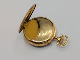 a gold colored pocket watch with a gold colored dial