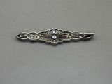 a close up of a silver pin with a diamond on it