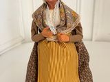 figurine of a woman in a yellow dress and bonnet sitting on a white surface