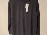Le pull est suspendu à un cintre accroché au mur.