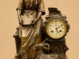 a statue of a woman sitting on a table next to a clock