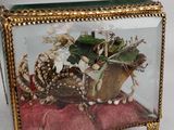 a glass box with flowers inside of it on a red cushion