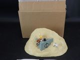 une petite figurine représentant un homme dans un bateau posé sur le sable