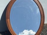 a mirror sitting on the ground with a sky in the background
