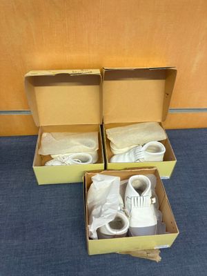 deux cartons contenant des chaussures, posés par terre