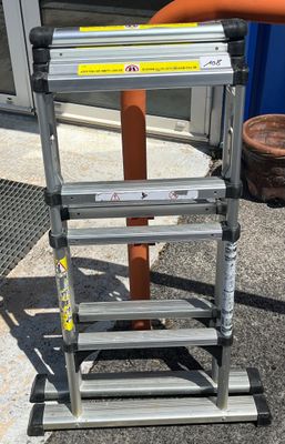 a ladder that is sitting on the ground next to a pole