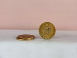 a gold coin sitting on top of a white counter next to a pink wall