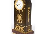 une horloge posée sur un support sur fond blanc