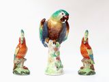 three figurines of parrots sitting on top of each other