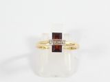 a close up of a gold ring with a red stone and a diamond