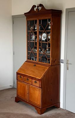 a wooden cabinet with a glass door in the corner of a room