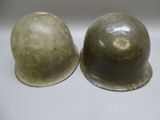 pair of military helmets sitting on top of each other on a white surface